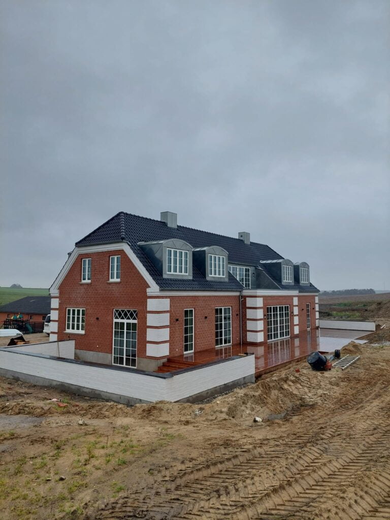 Nybygget murstenshus med sort tag under opførelse