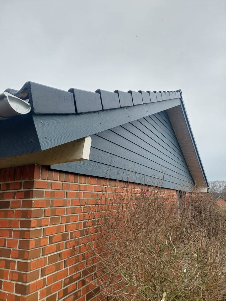 Murstenshus med mørkeblåt træværk og tagrende