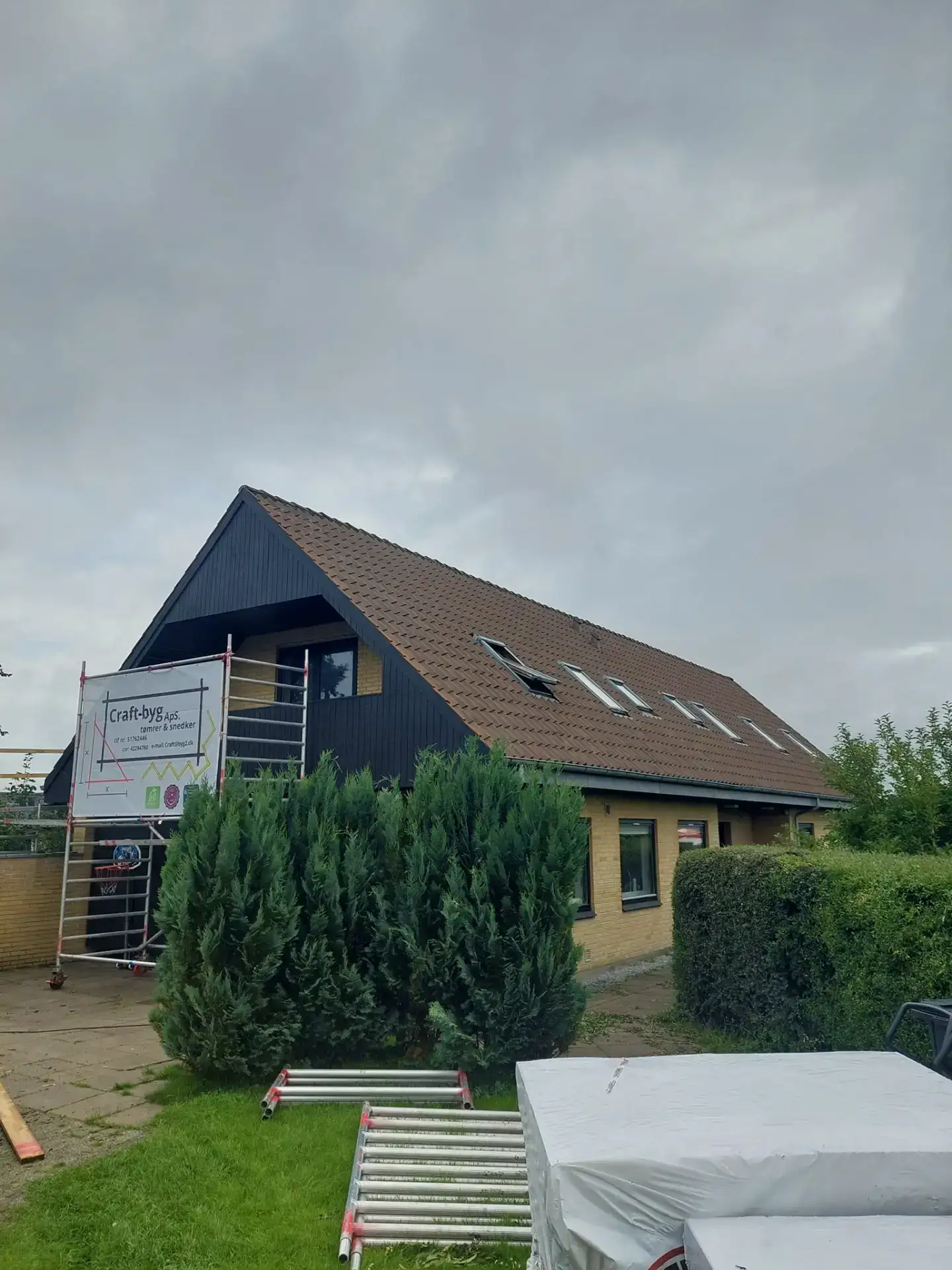 Moderne tagkonstruktion med skråtag og store vinduer, der kombinerer funktionalitet og æstetik i et.