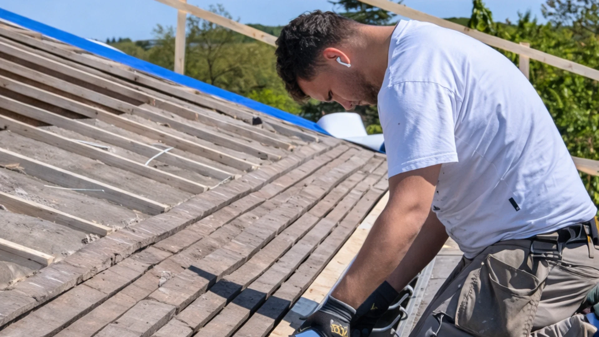 Mand lægger tagsten på tag med værktøj og sikkerhedsudstyr.
