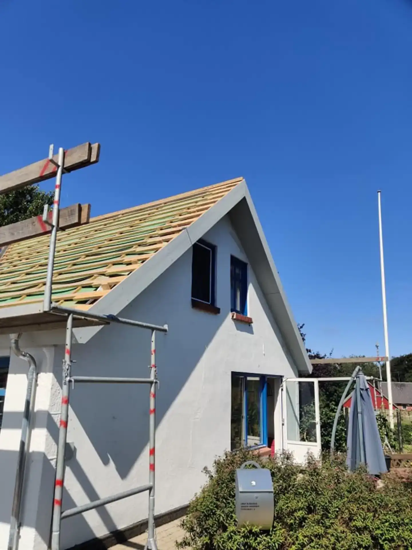 Fritidsvilla med skråt tag og store vinduer under opbygning i solrigt vejr.