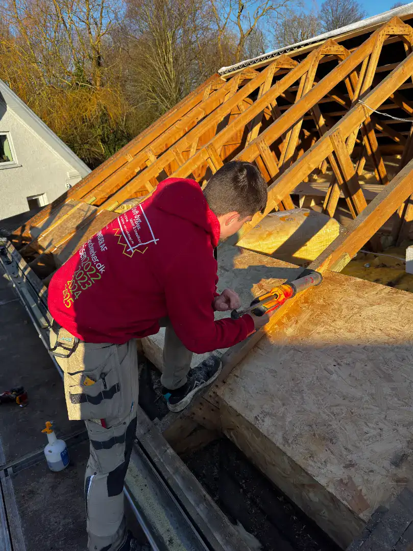 Tømrer arbejder på at opbygge en tagkonstruktion til et nyt hus.